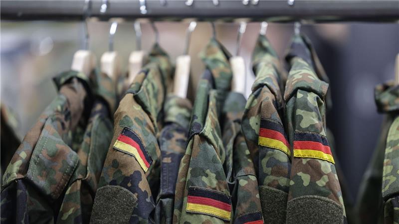 Zusehen sind Uniformen der Bundeswehr, die an Kleiderhaken hängen.