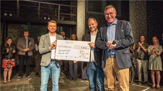 1500 Euro spenden die Rotarier des Rotary Clubs Goslar-Nordharz nach dem Ende der zweiten Premiere von „Bad Girls“ am Donnerstag: Andreas Poppe (li.) und Präsident Bernd Giesel (rechts) übergeben den Scheck noch auf der Bühne an den Vorsitzenden des Vereins, Dennis Semper.