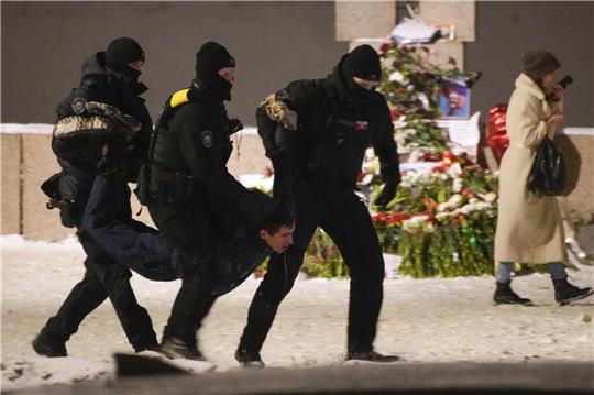 16. Februar, Russland, St. Petersburg: Polizeibeamte halten einen Mann fest, der Blumen zu Ehren von Alexej Nawalny an einem Denkmal für die Opfer der sowjetischen Unterdrückung in St. Petersburg niedergelegt hat. Archivfoto: Uncredited/AP/dpa