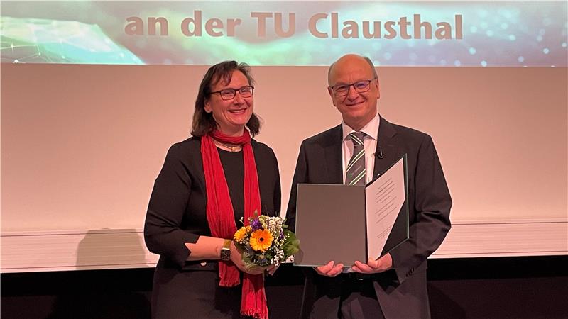 Das Bild zeigt links Sylvia Schattauer, Präsidentin der TU Clausthal, mit einem Blumenstrauß und rechts Professor Daniel Goldmann mit seiner Abschiedsurkunde.