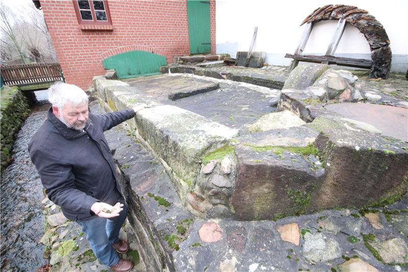 Abbenrodes Heimatvereinschef Andreas Weihe an der Zisterne der Wassermühle Otto: In der Hand hält er Bruchstücke, die aus den Fugen herausgebrochen sind. Foto: Gereke