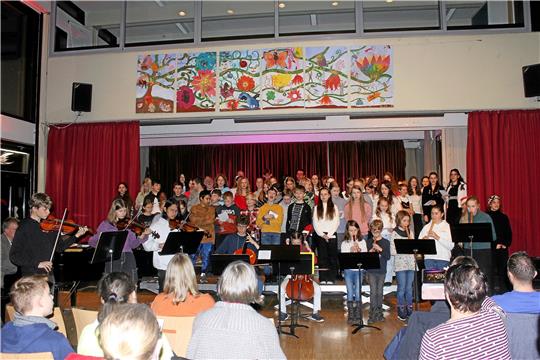 Abendliches Weihnachtskonzert in der RKS: Das Orchester singt bekannte Weihnachtslieder und stecken damit die Zuschauer an: Gemeinsam singen sie Lieder wie O du fröhliche, O Tannenbaum und Stern über Bethlehem. Foto: Jenzora