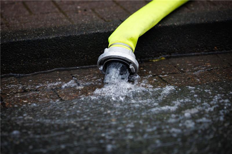 Gasleitungen in Northeim wegen Hochwasser unterspült Abgepumptes Wasser aus einem Haus fließt aus einem Schlauch auf die Straße.