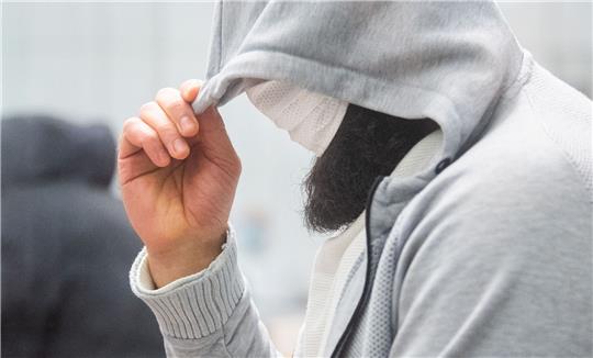 Abu Walaa, mutmaßlicher Anführer der Terrormiliz Islamischer Staat (IS) in Deutschland, steht im Oberlandesgericht hinter einer Glasscheibe.