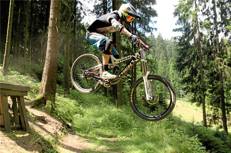 Ein Mountainbiker im Racepark Schulenberg, er fährt über eine Rampe aus Holz.