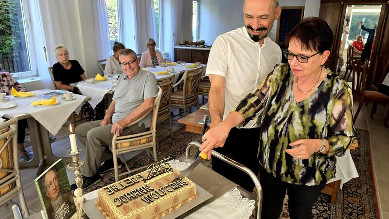 Der junge Werther geistert durch das Goethehaus in Altenau Achim Kapelle und Brigitte Wagener schneiden die Goethe-Torte an, die anschließend an den Tischen serviert wird.