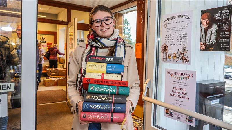GZ-Volontärin Hanna Schlimme steht mit einem großen Stapel Bücher in den Armen vor dem Eingang zur Stadtbibliothek Clausthal-Zellerfeld.