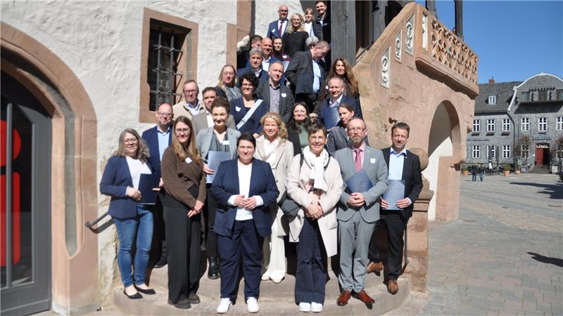 Gruppe von Menschen steht auf einer steinernen Außentreppe vor einem historischen Gebäude bei sonnigem Wetter