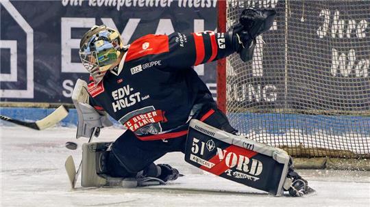 Eishockeytorwart in kompletter Ausrüstung in einer Abwehrhaltung vor dem Tor auf dem Eis.