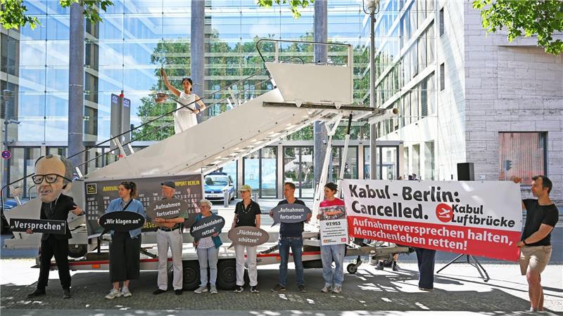 Aktivsten stehen während einer symbolischen Protestaktion am Weltflüchtlingstag zur Unterstützung mehrerer Klagen von Afghanen gegen die Bundesregierung vor dem Auswärtigen Amt.