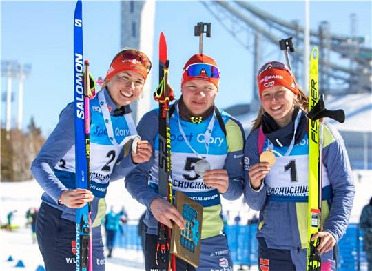 Albert Engelmann wird nach seinem Silberlauf von Julia Tannheimer (re.) und Julia Kink in die Mitte genommen, die dem Deutschen Skiverband je einen Doppelsieg in Sprint und Verfolger bescherten. Foto: Yevenko/IBU
