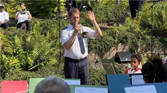 Alexander Valerstein spielt beim Konzert der Heilsarmee im Kurpark mit der einen Hand Trompete und mit der anderen dirigiert er seine Schüler.
