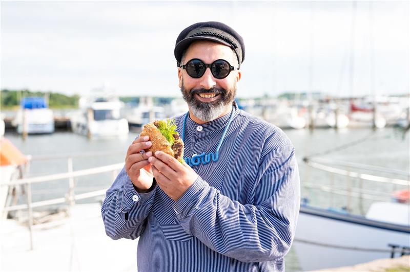 Ali Alam mit einem Fischbrötchen am Hafen an der Trave.