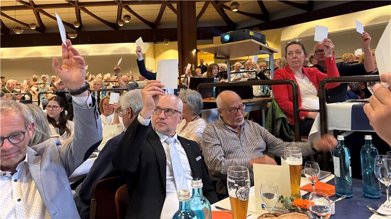Das Foto zeigt viele Menschen, die eine Stimmkarte hochhalten.