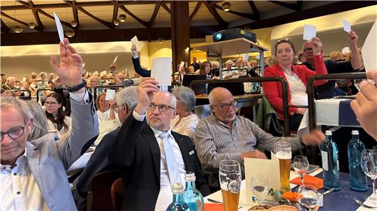 Das Foto zeigt viele Menschen, die eine Stimmkarte hochhalten.