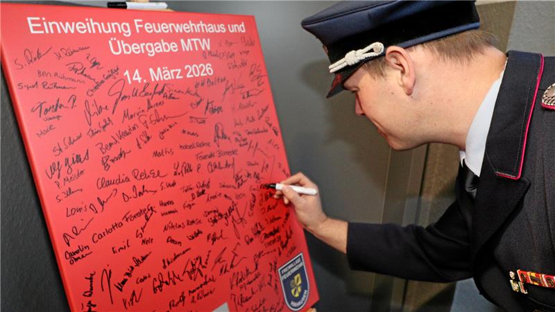 Ein Feuerwehrmann unterschreibt auf einer Tafel.