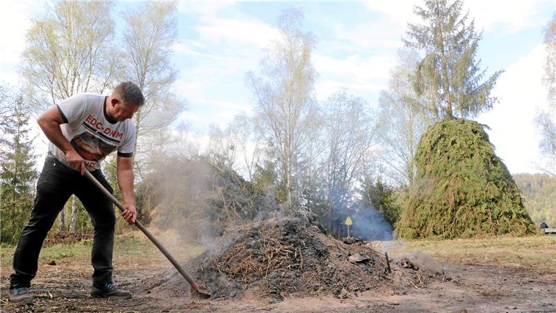 Aller guten Dinge sind drei: Heiko Horn schippt am Feuerhaufen von Karfreitag, dahinter links der Haufen fürs Lockfeuer, rechts der eigentliche Osterfeuerhaufen mit der Fichte in der Mitte.