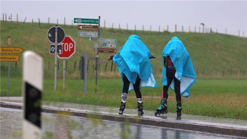 Bilder des Tages Alles eine Frage der richtigen Kleidung - Zwei Inline-Skaterinnen fahren im strömenden Regen im bayerischen Roßhaupten.