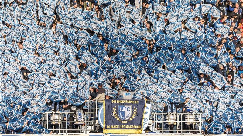 Alles weiß und blau. Fans vom 1. FC Magdeburg feuern ihr Team mit Fahnen beim Spiel gegen Holstein Kiel an.