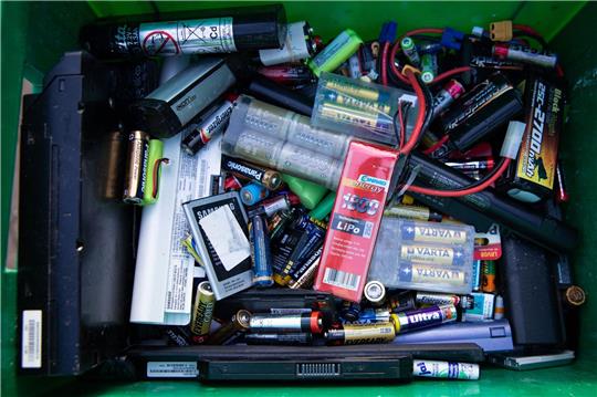Alte Batterien und Akkus in einem Sammelbehälter auf einem Recyclinghof.