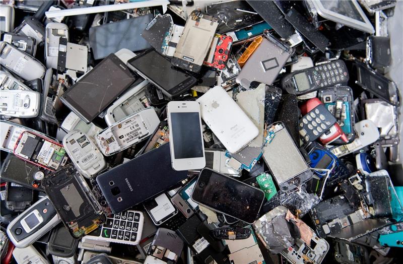 Alte Handys und Smartphones liegen in einem Container, ehe sie geschreddert werden.