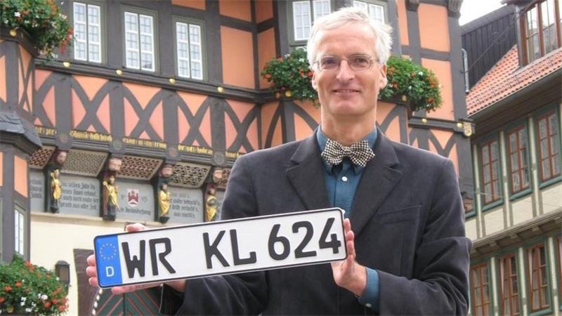 Ein Mann steht vor dem Rathaus Wernigerode und hält ein Kennzeichen in der Hand.