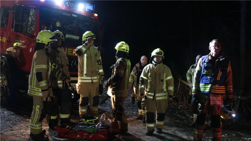 Mehrere Feuerwehrleute stehen in der Dunkelheit und in Einsatzkleidung vor einem Feuerwehrfahrzeug.