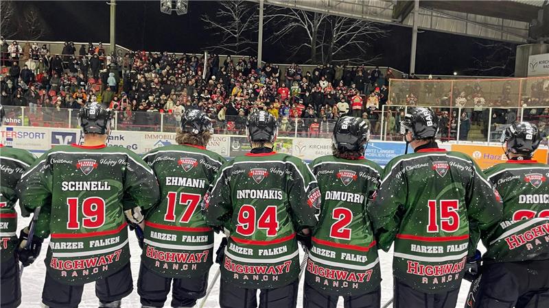 Sechs Eishockeyspieler in grünen Trikots stehen vor Zuschauern in einem Stadion.