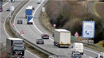 Eine viel befahrene, vierspurige Straße mit Baustellenschildern am Rand.
