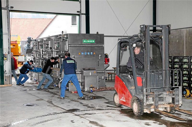 Am Halleneingang müssen alle Mann mit anpacken und die neue Anlage, die auf Panzerrollen gesetzt wurde, in Position bringen.