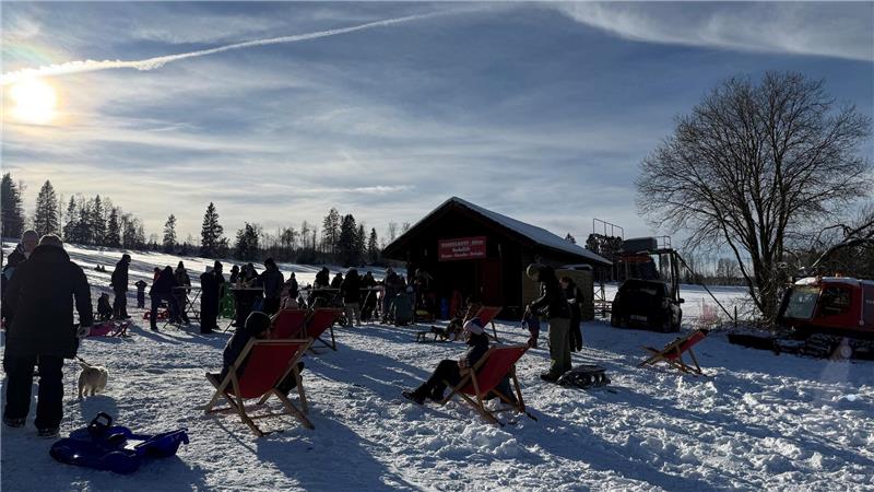 Menschen stehen vor einer Ski-Hütte, um sich auf das Ski- und Schlittenfahren vorzubereiten.