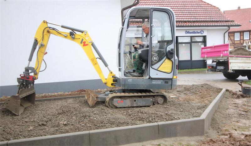 Lutter geht den Tiefbauarbeiten im Dorf auf den Grund Am Lutteraner Finanzcenter, das Öffentliche und Landessparkasse beheimatet, sind Garten- und Landschaftsbauer mit einem Minibagger aktiv.