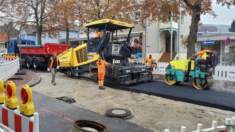 Das Bild zeigt eine Sraßenbaustelle, auf der gerade eine Bitumenschicht eingebaut wird.