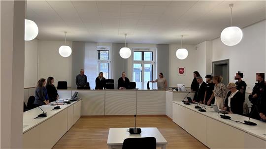 Ein Gerichtssaal, in dem Menschen stehen.