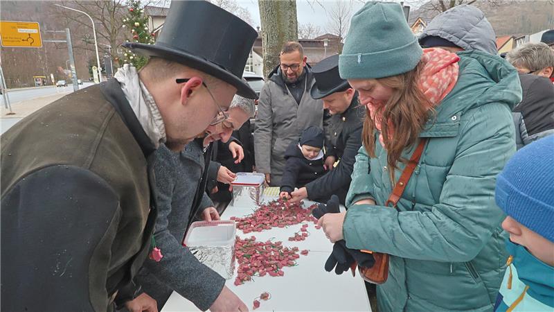 Der GZ-Schweinchenverkauf läuft in Goslar auf Hochtouren Mehrere Personen stehen an einem langen weißen Tisch im Freien, auf dem sich viele kleine rote Glücksschweinchen befinden