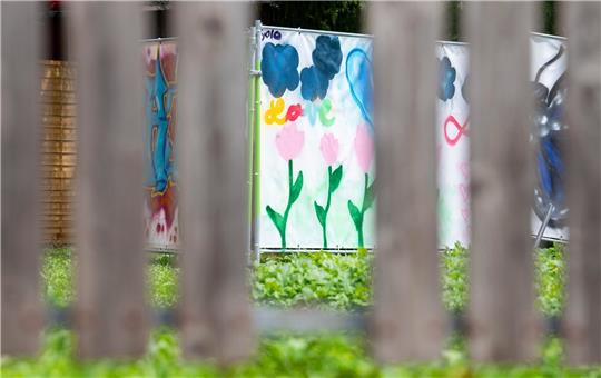 Am Rand einer Brachfläche hängen von Kindern gestaltete Plakate an Bauzäunen. An dieser Stelle stand das Haus, vor dem der Messerangriff auf zwei Schülerinnen stattfand.