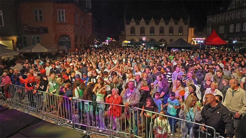 Große Menschenmenge vor einer Bühne bei einem Altstadtfest in der Nacht mit historischen Gebäuden im Hintergrund