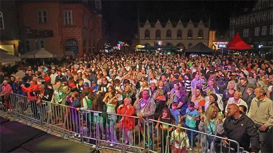 Große Menschenmenge vor einer Bühne bei einem Altstadtfest in der Nacht mit historischen Gebäuden im Hintergrund