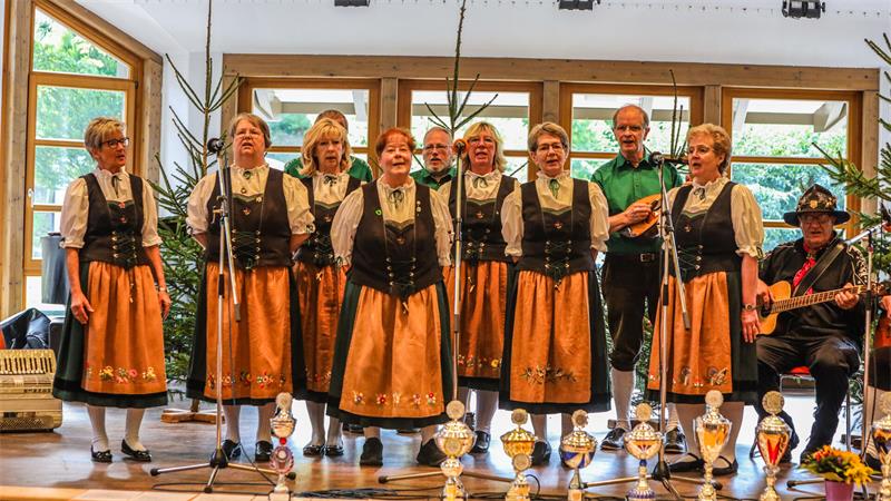 Frauen und Männer in Trachten stehen auf einer Bühne.

