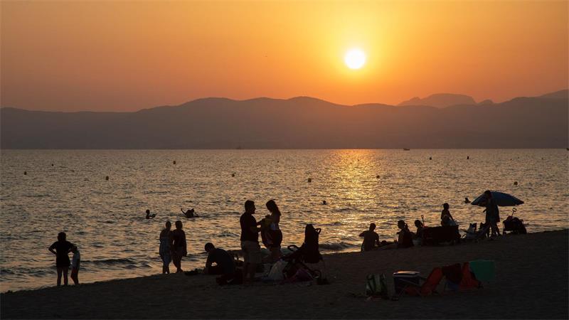 Rekordwärme in Europas Meeren geht auf Klimawandel zurück Am Strand von Playa de Palma auf Mallorca baden Menschen bei Sonnenuntergang im Meer. (Archivbild)