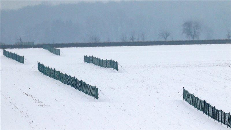 Schneefangzäune stehen auf einem schneebedeckten Feld.