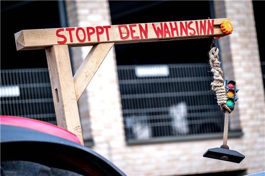 An einem Traktor ist bei einer Demonstration von Bauern ein Galgen befestigt, an dem eine Ampel hängt.