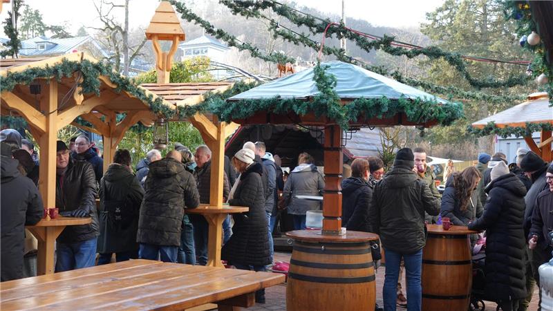 An überdachten Tischen und in kleinen Hütten stehen und sitzen die Besucher.