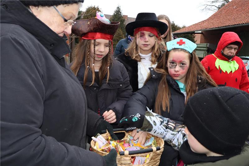 Verkleidete Kinder nehmen Süßigkeiten aus eine Schale. 