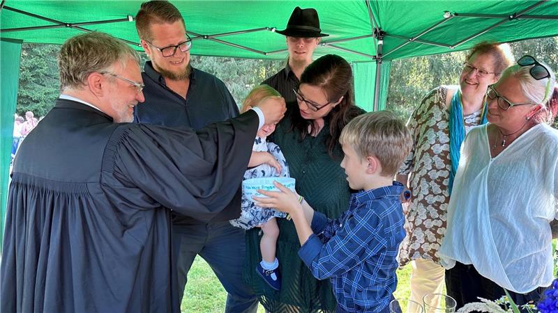 Abschied nach Jahrzehnt: Pastor Dittmann behält den Harz im Herzen Pastor André Dittmann tauft bei einem Tauffest ein Kind. Drumherum steht die Familie des Mädchens.