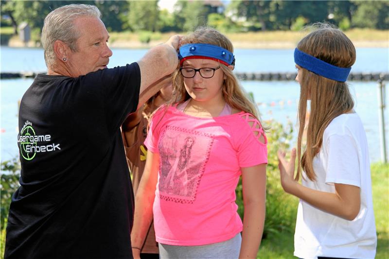 Ferienpassaktion: Lasergame im Oberharzer Waldseebad Andreas Bittner von Lasergame Einbeck legt den Kindern die Stirnbänder an, die jeden Treffer zwischen Kopf und Bauch aufzeichnen.