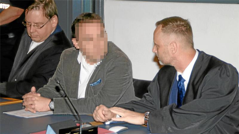 Ein Mann sitzt während einer Verhandlung auf der Anklagebank zwischen seinen Verteidigern. Sein Bild ist auf dem Foto unkenntlich gemacht.