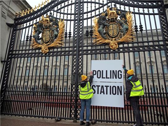 Anhänger der Kampagnengruppe Republic hängen ein Wahllokalschild ans Geländer des Buckingham Palace in London.