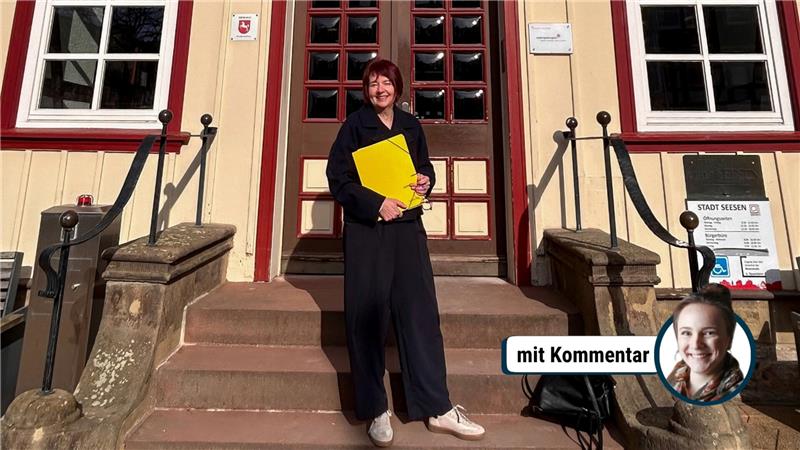 Person mit schwarzer Kleidung und weißer Schuhen steht auf einer Treppe vor einem Gebäude und hält eine gelbe Mappe