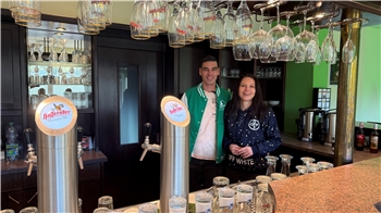 Ein Ehepaar lacht hinter einer Theke in die Kamera